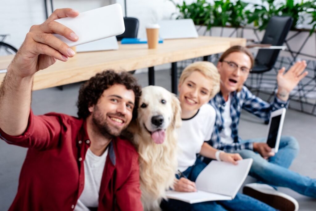 happy young people taking selfie with dog in office