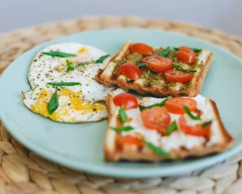 over-well-fried-eggs-and-toasts-with-cherry-tomatoes-pesto-green-onions-and-cottage-cheese_t20_kz31z4-min